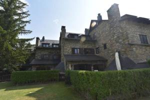 a large stone building with a hedge in front of it at Acogedor apartamento de montaña con jardín y piscina - VU-HUESCA-23-182 in Benasque