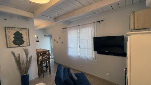 een woonkamer met een bank en een flatscreen-tv bij Jolie annexe du mas dans le cœur de la garrigue nîmoise in Nîmes