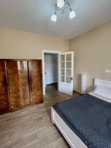 ein Schlafzimmer mit einem Bett und einem Holzschrank in der Unterkunft Riverfront Apartment in Tbilisi City