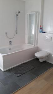 a white bathroom with a tub and a toilet at Hinter'm Mäuerchen 