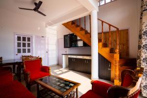 a living room with a staircase and red chairs at Brown Stone Villa in Bhīm Tāl