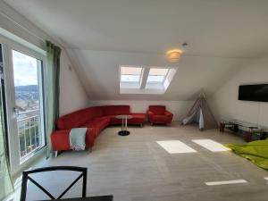 uma sala de estar com um sofá vermelho e uma grande janela em Ferienwohnung Zartgrün Blumberg em Blumberg