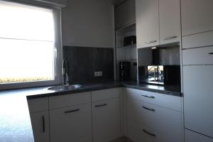 eine Küche mit weißen Schränken und einer Spüle und einem Fenster in der Unterkunft STRANDLIEBE 100 qm Gartenwohnung (eingezäunt), 15 Gehminuten zum Strand in Neukirchen + 46 Fotos