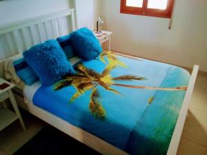 a bed with blue pillows and a palm tree on it at Sea View Penthouse Apartment Monte Pego in Pego