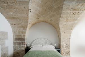 1 dormitorio con 1 cama en una pared de piedra en Clementia Guest House, en Altamura