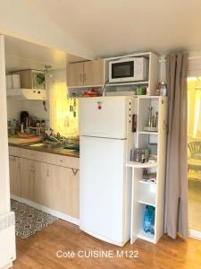 een keuken met een witte koelkast en een magnetron bij locationestivale40 Bungalow petit budget océan forêt in Bias