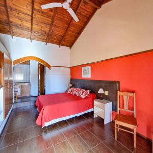 een slaapkamer met rode muren en een bed en een stoel bij POSADA NEHUEN in Villa General Belgrano