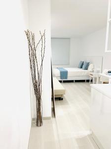 a white room with a bed and a vase on the floor at Apartamentos Ruta da Auga in Ribadumia