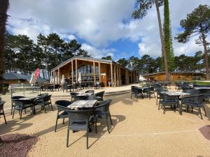 a group of tables and chairs in front of a building at Vacances sous les pins, près de la mer, 6-8 pers,bien équipé, piscine in Saint-Julien-en-Born