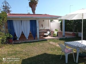 a patio with a table and chairs and an umbrella at Villa Amenta in Fontane Bianche