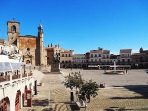 une place de la ville avec une tour de l'horloge et une église dans l'établissement Hogar acogedor en Trujillo, à Trujillo