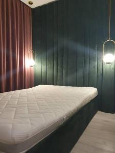 a bed in a room with a green wall and two lights at Butas Šiaulių centre in Šiauliai