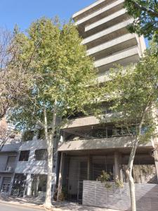 a tall building with trees in front of it at Pichincha Guemes Balcon in Rosario