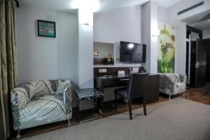 a living room with a couch and a desk with a television at Hotel Dolce International in Skopje