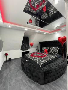 Phöenixpalace Whirlpool & Infarotsauna في دورتموند: غرفة نوم بسرير أسود عليها قلوب حمراء
