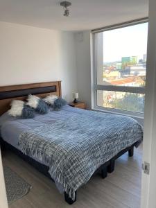a bedroom with a bed and a large window at Departamento Central Valdivia in Valdivia