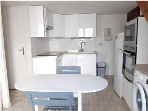 cocina blanca con mesa blanca y sillas en Maison T2 Terrasse Mezzanine, en Le Grau d'Agde