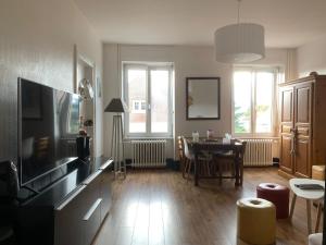 a living room with a television and a dining room table at Au kouglof avec Netflix in Colmar
