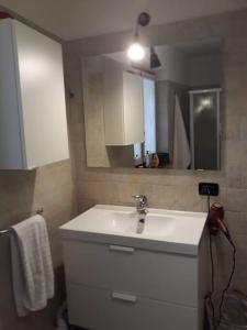 uma casa de banho com um lavatório branco e um espelho. em Mini Midlake codice cipat 022229-AT-410061 em Mezzolago