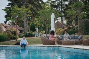 two women and a child sitting next to a swimming pool at Domaine des Chailloux 