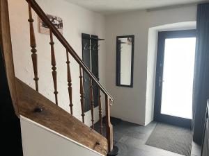 a hallway with a wooden staircase with a mirror at Hinter'm Mäuerchen 