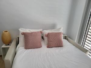 - un lit blanc avec 2 oreillers roses dans l'établissement Cosy room in Morden apartment, à Luxembourg