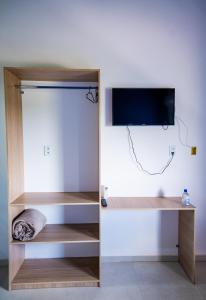 a shelf with a tv on a wall at Flats 2 Locação Penedo RJ in Penedo