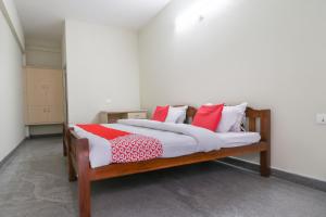 a bedroom with a bed with red and white pillows at Appas Residency in Ambalavayal