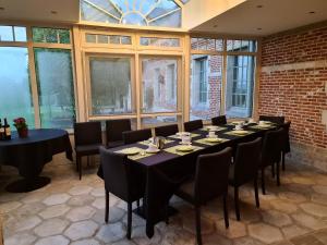 uma sala de jantar com mesas, cadeiras e janelas em Eyckenmolen B&B em Lierde
