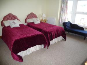 a bedroom with two beds and a blue chair at Ivy Hall in Wootton Bridge
