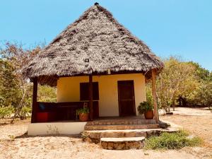 a small hut with a thatched roof at Ushongo Beach Cottages - Family House in Tanga