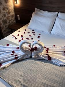 Dos cisnes están haciendo forma de corazón en una cama con rosas. en Double Bee Villa with private pool, en Agios Konstantinos