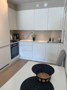 a kitchen with white cabinets and a table at Leilighet sentralt i Tromsø in Tromsø