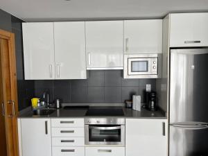 Una cocina con gabinetes blancos y electrodomésticos de acero inoxidable. en Elcano Bermeo By Urdaibai Rentals, en Bermeo 6 fotos más