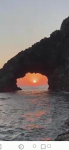 an arch in the ocean with a sunset in the background at Madilì in Pantelleria