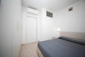 a white bedroom with a bed and a door at Miramare_5 appartamento in Castelsardo +14 photos