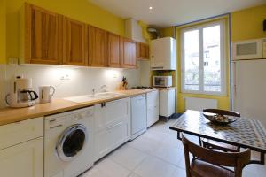 a kitchen with white appliances and a table with chairs at Jourde Vacances in Le Puy en Velay