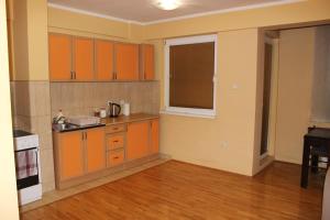 an empty kitchen with orange cabinets and a window at Apartman Romana in Doboj
