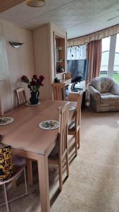 a kitchen and living room with a wooden table and chairs at Summerlands, Ingoldmells 8 berth caravan in Skegness +14 photos