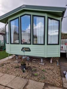 斯凱格內斯的住宿－Summerlands, Ingoldmells 8 berth caravan，坐在院子里的绿色小房子