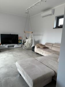 uma sala de estar com um sofá e uma rede de descanso suspensa em Atpuutas māja pie Jūras-Riņķi em Saulkrasti