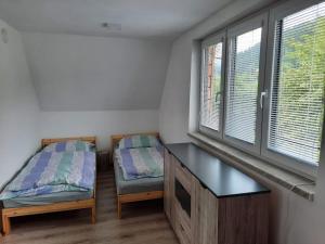 a room with two beds and a desk and windows at Objevte krásu Beskyd , navštivte chatu Lojza in Staré Hamry