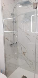 baño con paredes de mármol blanco y puerta de cristal en la casa de isa en aveiro, en Aveiro