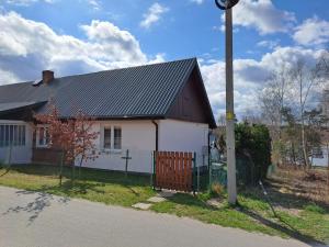 a white house with a black roof and a pole at Domek u Jadzi in Zwierzyniec +6 photos