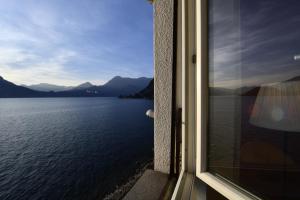 een raam met uitzicht op het water en de bergen bij Margherita House in Varenna