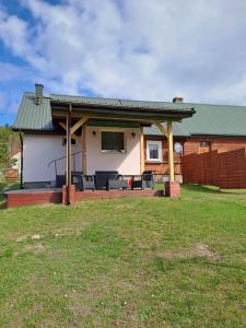 a house with a porch with a green roof at Domek u Jadzi in Zwierzyniec