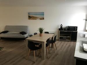 ein Wohnzimmer mit einem Tisch, Stühlen und einem Sofa in der Unterkunft Appartement numéro 4 ou numéro 8 in Savigné-lʼÉvêque