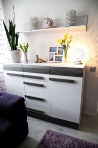 a white dresser in a living room with plants at Magnolia apartment in Liepāja