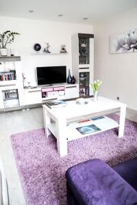 - un salon avec une table blanche et un tapis violet dans l'établissement Magnolia apartment, à Liepāja