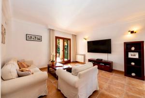 a living room with white furniture and a flat screen tv at Can Jaume Ferienhaus an der Playa de Palma mit Pool in Palma de Mallorca